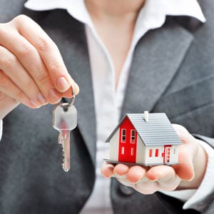 Person holding key and model house - Real Estate concept.- Burton Law Offices